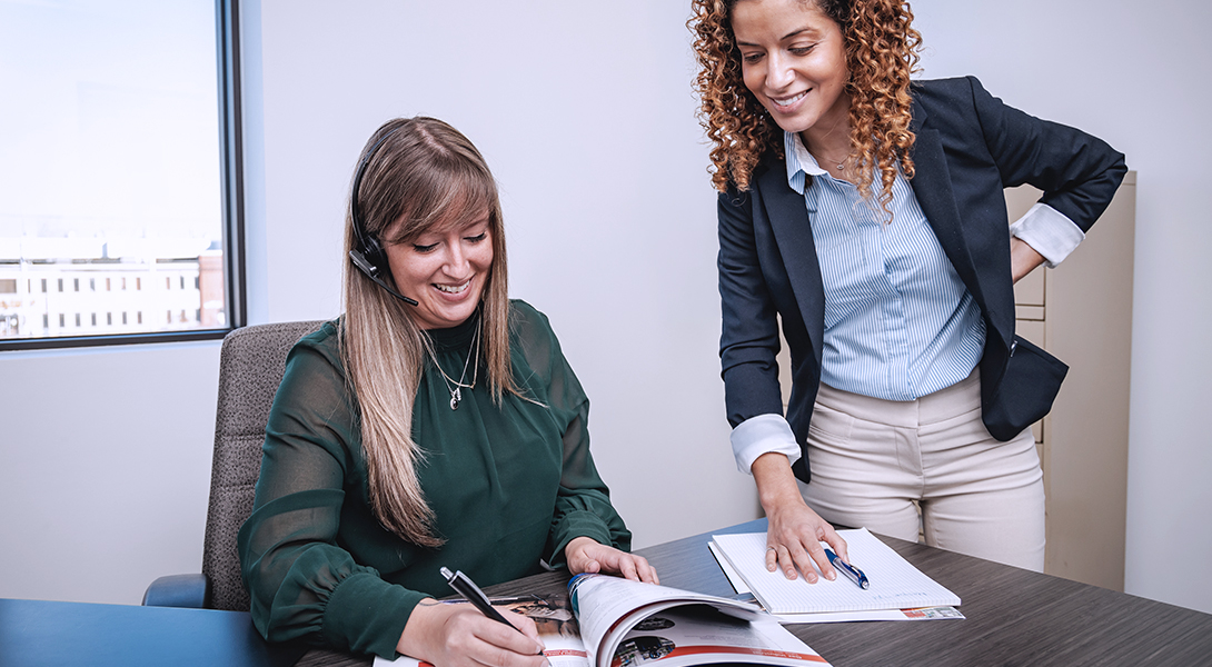 Two office employees collaborating over documents at a desk.