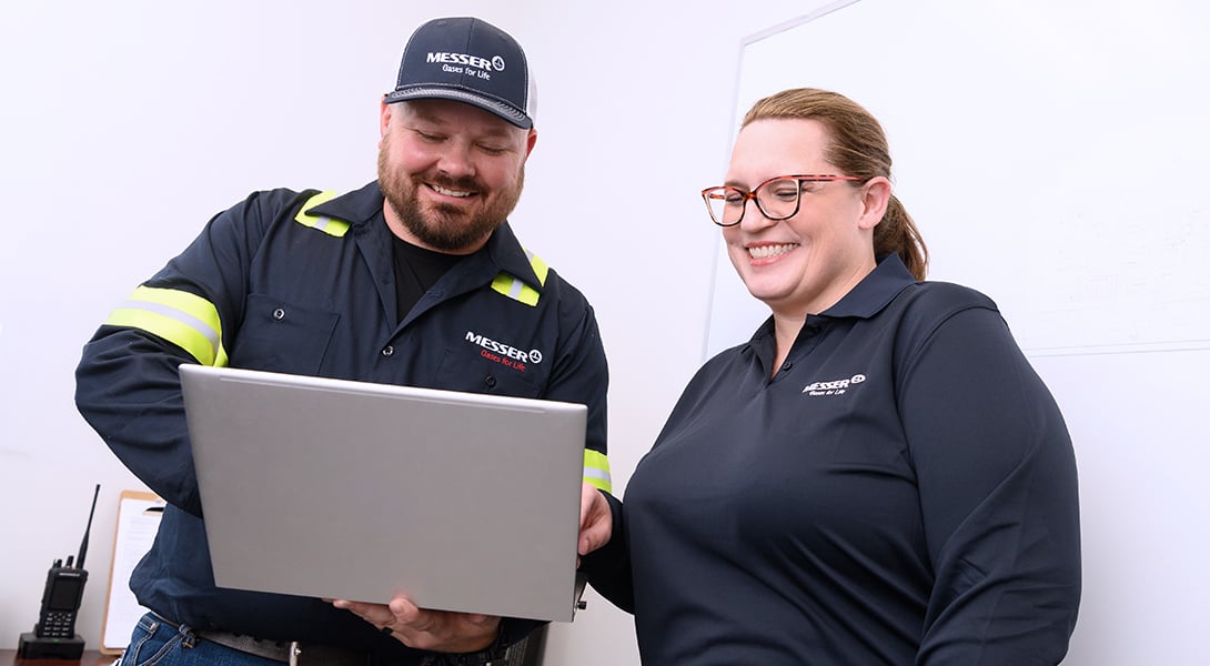 Two Messer employees reviewing information together on a laptop.