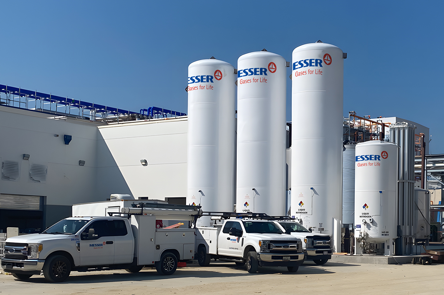 Messer bulk gas storage tanks outside an industrial facility, with service trucks parked in front.