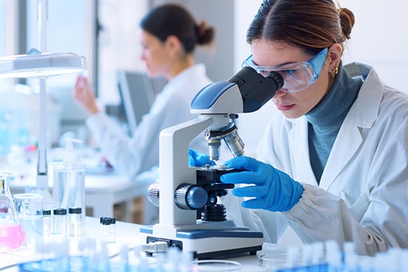 Scientist examining a sample under a microscope in a pharmaceutical laboratory.