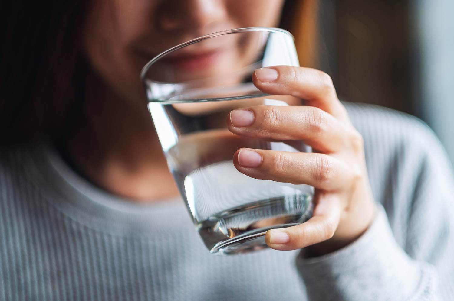 Closeup image of a woman holding a glass of water to drink